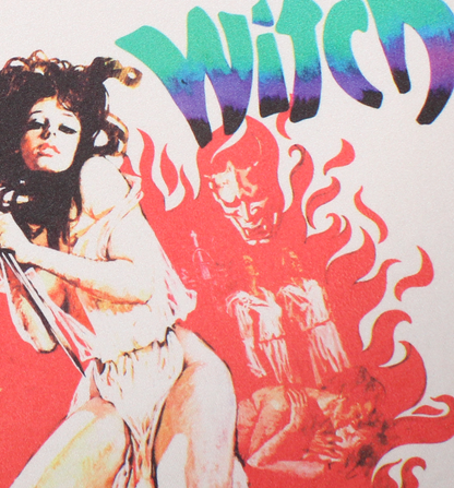 A close-up of a graphic print featuring a stylized nude woman on the left, red flames, a demonic face in the center, and the word 'Witch' in large green-to-purple gradient lettering at the top. A woman wearing a beige ringer T-shirt with black trim and a colorful graphic print featuring the text 'Virgin Witch' and a red flame design witch a woman holding a knife. Virgin Witch horror tshirt. 70s horror shirts. women's horror tees tshirts. women's horror movie ringer shirt. witch ringer tshirt. occult horror 