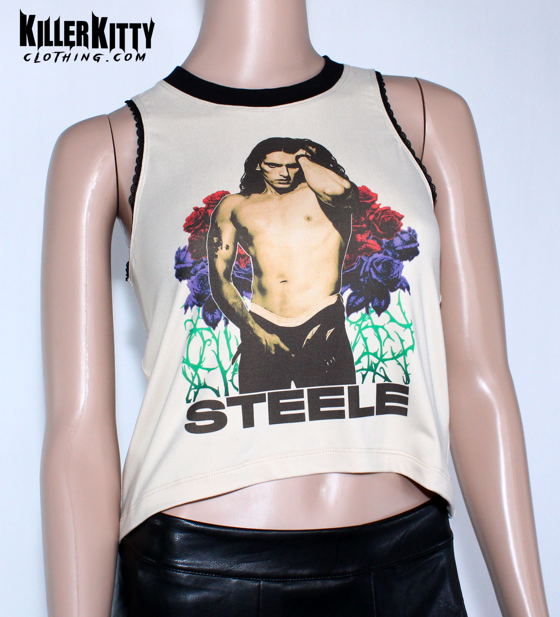 Women's Peter Steele relaxed fit, slouchy tank top. Type O Negative Top is tan/beige color, Asymmetrical hem, black lace-edged arms and black crew neck with an image of Peter Steele's Playgirl Cover. Band shirt.  Killer Kitty Clothing Alternative Brand. Mannequin wearing a sleeveless top with a graphic design and 'STEELE' text on a tan background