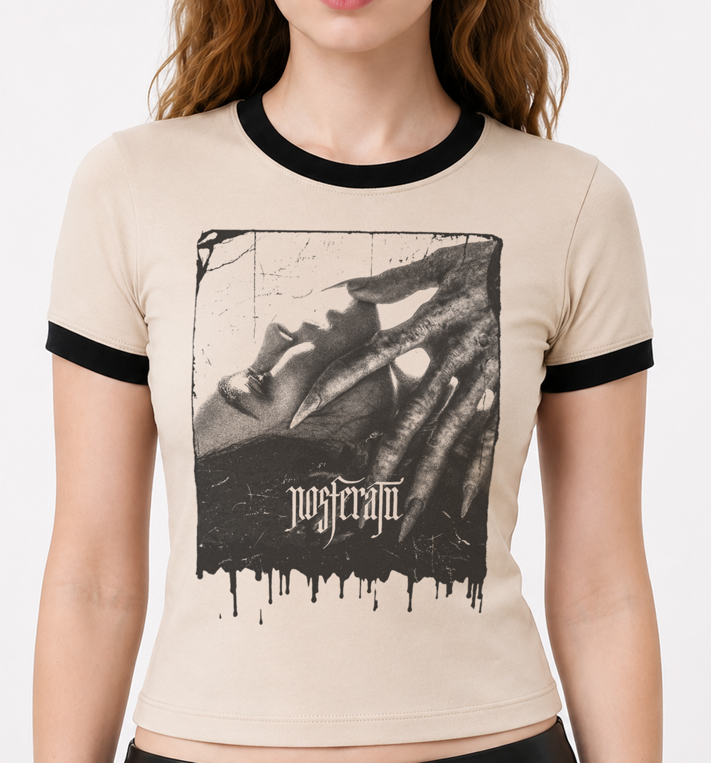 A woman wearing a beige ringer T-shirt with black trim on the collar and sleeves, featuring a large black-and-white graphic print of a clawed hand and the word 'nosferatu' on the front. women's horror tshirts tops. nosferatu horror movie tshirt. women's nosferatu shirt. ladies horror tshirts. horror movie tees for women. dracula horror shirtfor women. ladies dracula tshirt. punk horror vampire tshirts for women. halloween tshirts for women. goth horror shirts for ladies women. gothic vampire horror tshirts 