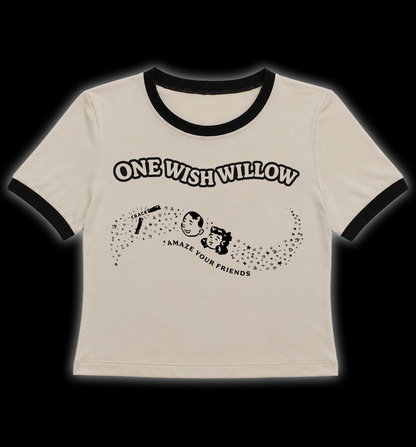 A tan ringer t-shirt with black trim on the collar and sleeves, featuring a black graphic print of a cartoon character and the text 'ONE WISH WILLOW' and 'AMAZE YOUR FRIENDS'. One wish willow crop top t shirt. One wish willow women's plus size t shirt. Obsession one wish willow retro ringer crop top tee shirt. Obsession horror movie t shirt crop top alternative goth clothing. Women's horror movie dress and t shirts. 
